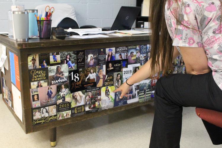 OCHS teacher Erin Bunch points to the graduation announcements of former students who have moved on to pursue careers in the healthcare field. (Photo/Darden Hearn)