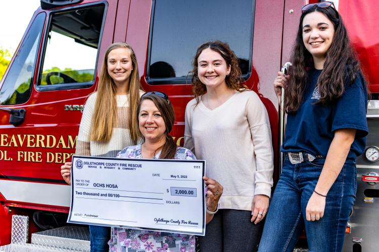 Harley Grace Hayes (from left), healthcare science teacher Erin Bunch, Elisse Griffiths and Kate Spearing display the $2,000 check they received from the Beaverdam Volunteer Fire Department to help sponsor their trip to the HOSA International Leadership Conference. (Photo/Jack Casey)