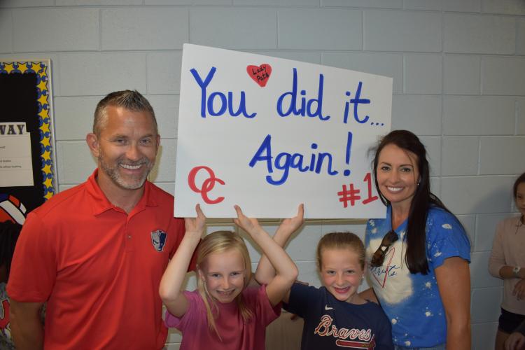 Girls track coach Tim Stoudenmire and assistant coach Penni Stoudenmire pose with OCES students during the team’s championship parade. The couple, with several other coaches, led the team to their second straight state title. (Photo/Thomas Ehlers)