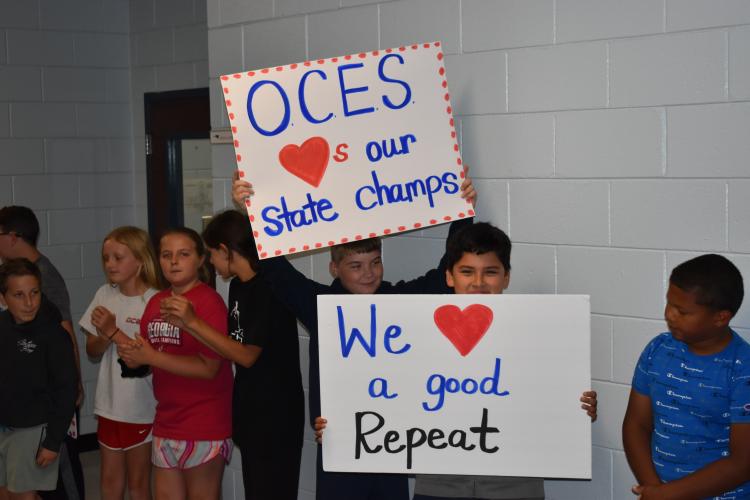 Students at Oglethorpe County Elementary school hold up signs congratulating the OCHS girls track team. The elementary school played music, cheered and displayed signs for the athletes as they paraded through the school. (Photo/Thomas Ehlers)