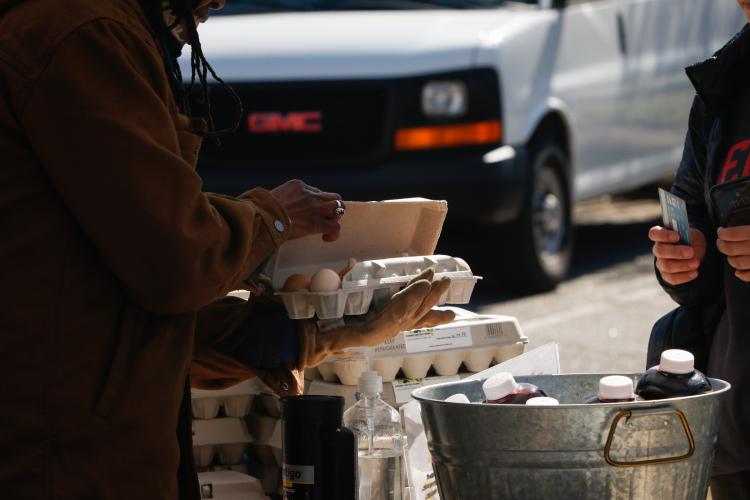 Tamita Brown shows a customer the quality of her chicken eggs before a purchase at the Athens Farmers Market in March. Brown owns Caribe United, a farm in Crawford. (Photo/Basil Terhune for The Oglethorpe Echo)