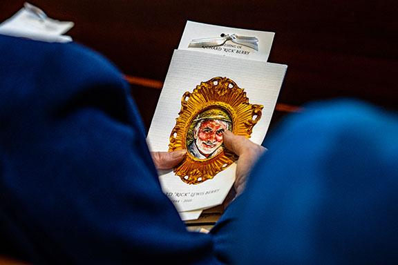 A guest at the memorial for Rick Berry holds the information pamphlet for the service. (Photo/Jack Casey)