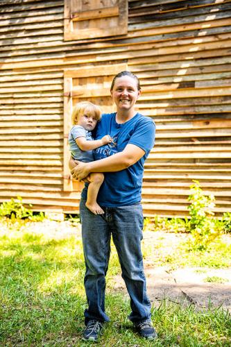 Shannon Haynie holds her son Roman in front of her barn on Elberton Road. Shannon and her mom, Donna Wetterlund, share a love for history and did not want to see the nearly 130-year-old structure torn down. (Photo/Jack Casey)