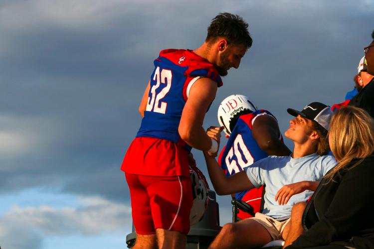 Long snapper Caleb Hall offers encouragement to freshman teammate Dalton Hilley, who dislocated his hip in practice on Sept. 27 and had to watch the game from a wheelchair in the stands. (Aisha Shulz/The Oglethorpe Echo)