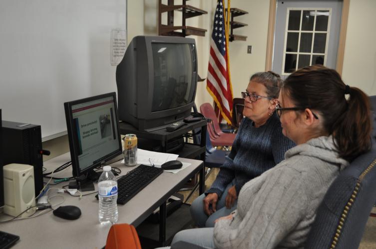 Bus driver trainer Felicia Dellaria (left) and Brandi Hokanson, a new bus driver trainee, watch a driving safety video last week. The trainees spent the morning completing a portion of the 12 hours of required class time for a CDL license. (Photo/Megan Fitzgerald)
