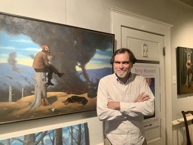 Artist Terry Rowlett poses with a painting at his Lexington home during the Art Crawl on Oct. 8, 2022. (Photo/Nimra Ahmad)
