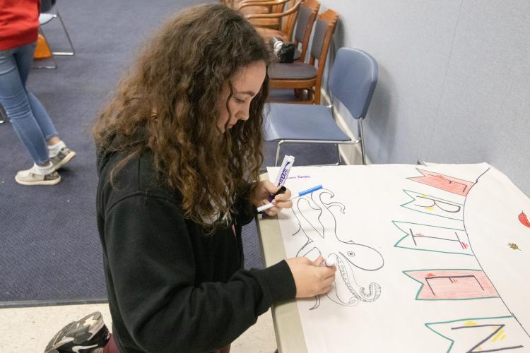 Charlie Roberts displays her artistic skills to draw an octopus on the Friendsgiving banner at the Oglethorpe County Library Friendsgiving on Nov. 15. (Katie Tucker/The Oglethorpe Echo)