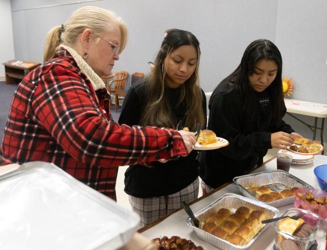 Sherry Lipinski (left) puts food on the plates of Alyssa (middle) and Chelsea Durie during the Oglethorpe County Library’s first Friendsgiving on Nov. 15. About a dozen teens participated in the event. (Katie Tucker/The Oglethorpe Echo)