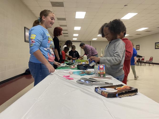 Teen leader Audrey Green (left) and fifth-grade student Breeyana Jones measure ingredients at the Cooking to Share program on Nov. 17. Adult and teen volunteers help the students with the cooking. (Erin Kenney, The Oglethorpe Echo)