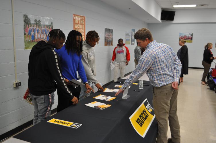 OCHS juniors Jaylen Banks, left, Kenyon Pass and Elijah Hood talk with Rick Chatfield, an operations manager at Yancey Bros. Co., at the college and career fair on Oct. 26. Representatives from colleges, businesses and the military talked with students about post-graduation job opportunities. (Photo/Megan Fitzgerald)