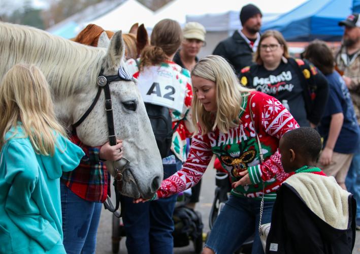 Lauren Anderson feeds one of the Echo Hill Farm horses at the  Maxeys Christmas Parade. The equine group positioned itself in  front of Mayor Warren Gilson’s house following the parade, so  folks could pet the horses and give them treats.