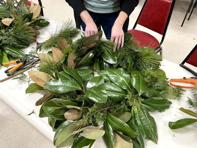 Kim Smith, a participant at the OCHS floral design class' wreath class on Dec. 8, finishes adding greenery to her wreath. (Erin Kenney/The Oglethorpe Echo)