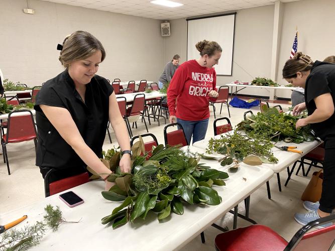 Rachel Hunt works on her wreath at the OCHS floral design class' wreath class on Dec. 8. In the background, Kaitlyn Marchant watches as Katie Scott works on her wreath. (Erin Kenney/The Oglethorpe Echo)