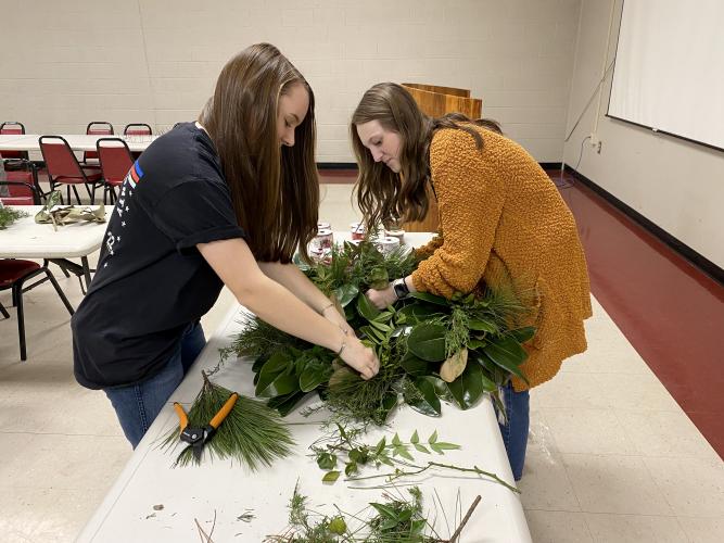 Callie Bridges (left) and Andee Dellinger work on an example wreath at a wreath making class on Dec. 8. The students are both OCHS freshman who are taking the floral design class. (Erin Kenney/The Oglethorpe Echo)