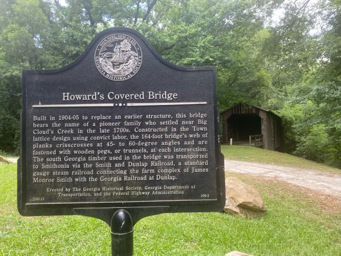 The historical marker tells the story of Howard’s Covered Bridge, which has been covered with graffiti. (Dink NeSmith/The Oglethorpe Echo) 