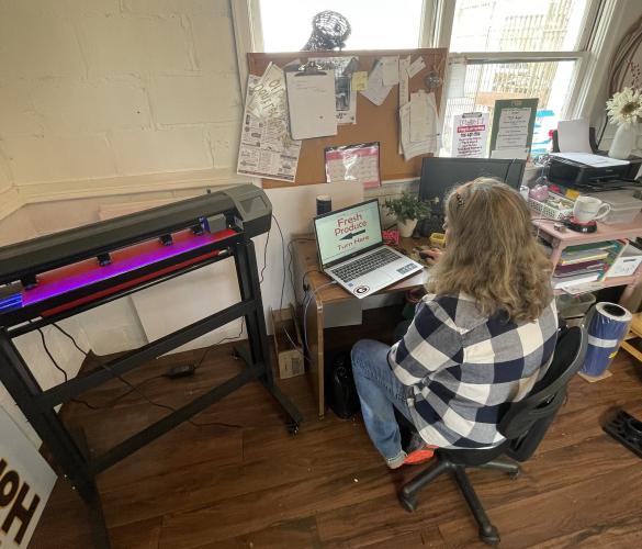 (Alex Bavosa/The Oglethorpe Echo) Holloway works in her office off Church Street in downtown Lexington, producing a sign for Strickland Produce, on Jan. 26, 2023. She calls the machine to her left the “cutter”.