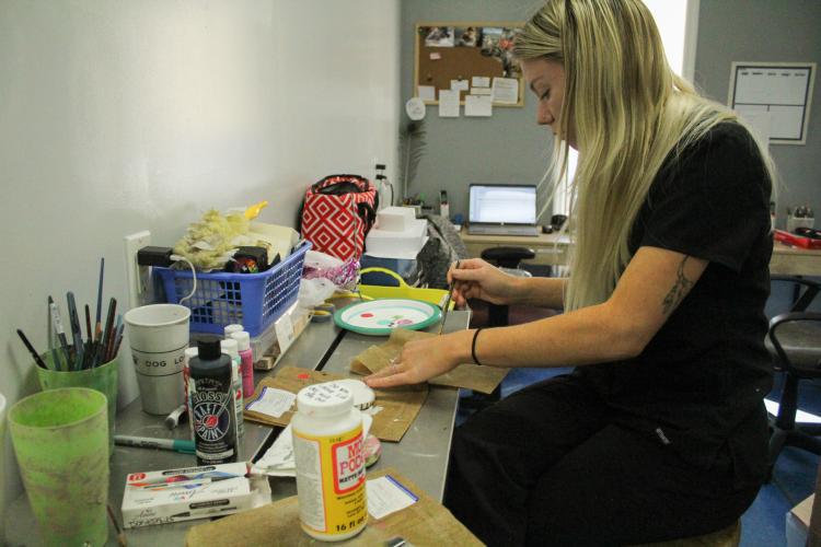 Veterinary technician Kameron Brownlee paints pawprints of euthanized patients so that owners may have a final token of their pet after the difficult procedure. The Oglethorpe Animal Clinic hopes to provide as much comfort and relief as possible to grieving clients. (Photo/Basil Terhune)