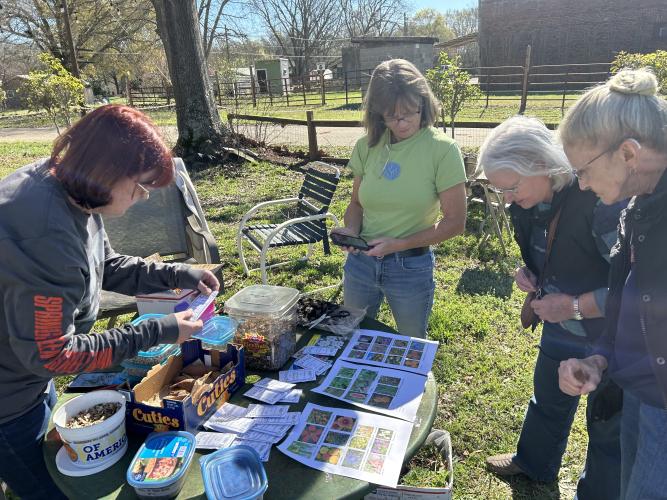 Volunteer gardeners Janet Smith (left) and Jackie Tripp (second from left) show the seeds they gave away at the Seed Swap. (SHELBY WINGATE/THE OGLETHORPE ECHO)