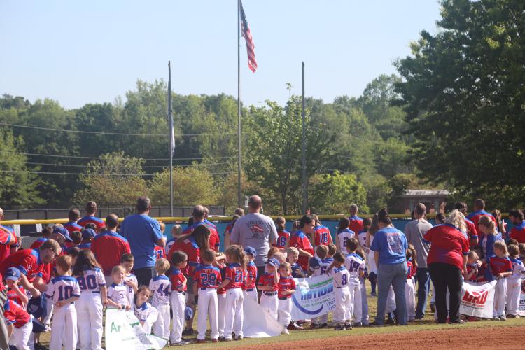 (JACK RHODES/THE OGLETHORPE ECHO) Little league players and coaches turn towards the flag as the national anthem plays during the opening ceremony. The national anthem was introduced by Scott Liedberg and sung by Jeremiah Stephens.