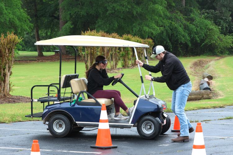 Oglethorpe County first responder Jacob Sledge leads an OCHS student wearing beer goggles through a course. The annual Ghost Out event brings awareness to the dangers of distracted driving for juniors and seniors. (LANDEN TODD/THE OGLETHORPE ECHO)