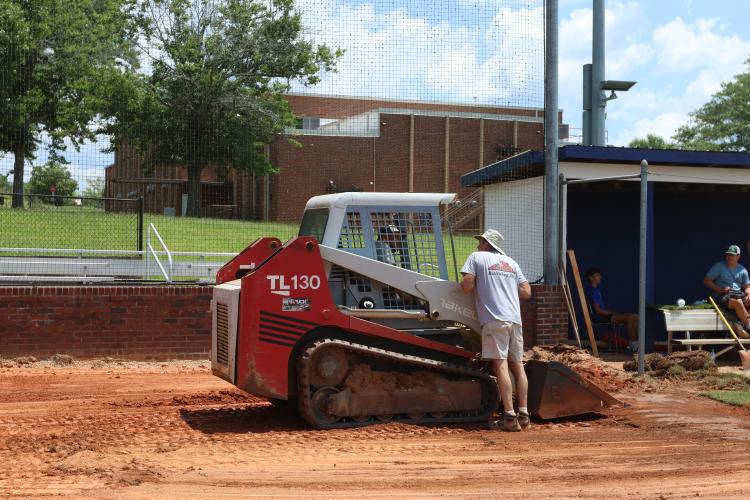 Bobby Sass chats with Caleb Sass, who is in the skid steer, at the OCHS baseball field on July 12. They helped level the infield. (LANDEN TODD/THE OGLETHORPE ECHO)