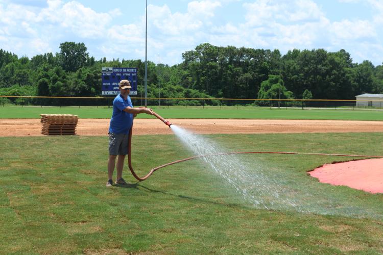 Jason Autry waters the new sod at the OCHS baseball field after the infield was leveled on July 12. The sod is from Deer Run Sod in Oglethorpe County. (LANDEN TODD/THE OGLETHORPE ECHO)