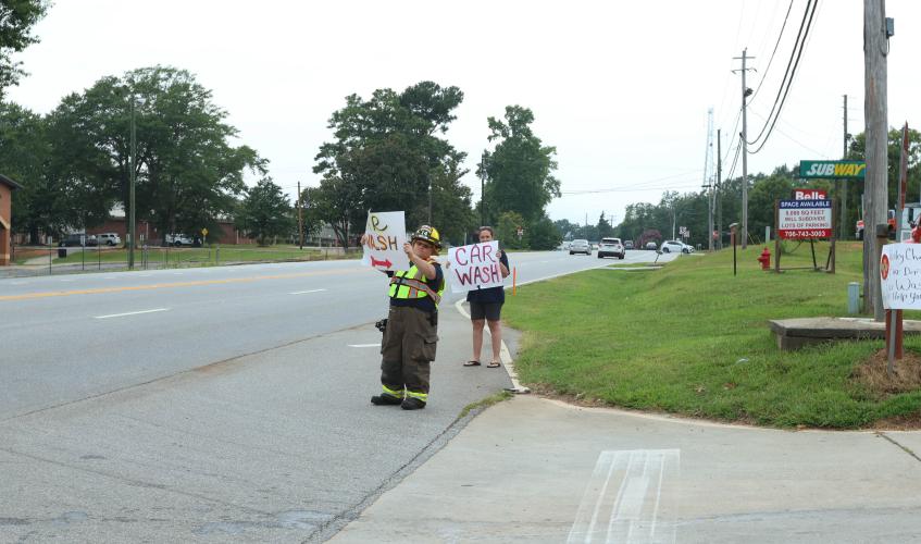 Robert and Lani Kline hold signs on Highway 78 to let folks know about the Wesley Chapel Volunteer Fire Department’s car wash fundraiser at Lexington Auto Parts last Saturday. The donations help the department purchase and maintain its equipment. (LANDEN TODD/THE OGLETHORPE ECHO)