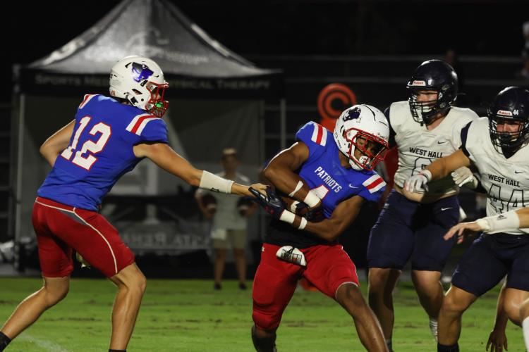 Senior quarterback Jayden Wallace (No. 12) hands the ball to Elijah Hood (No. 4) during Friday’s scrimmage. Hood and fellow senior Jake Turner will handle most of the running back duties this year. (LANDEN TODD/THE OGLETHORPE ECHO)