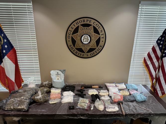 The Oglethorpe County Sheriff’s Office displays bags of drugs, including cocaine and fake Adderall, guns and about $8,000 in cash from a raid on a house on Collins Avenue in Lexington last Friday. (SUBMITTED PHOTO)