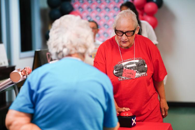 Cindy Lou Phelps hits the buzzer for the red team on Friday morning, Sept. 15, 2023. NBA All Star Dwight Howard hosted 'Family Feud' at the Oglethorpe Senior Center in Crawford, Georgia. (Photo/Sidney Chansamone)