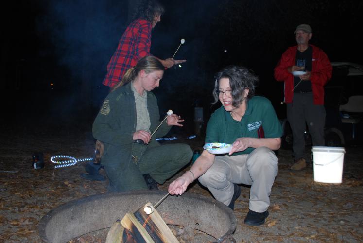 Lead clerk and park admin Lisa Nash and senior maintenance ranger of Victoria Bryant State Park Skylar Toth crouch down by the fire in order to get the perfect marshmallow roast. While Watson Mill Bridge State Park is in the process of getting a new manager, staff from the nearby state parks have been helping out.