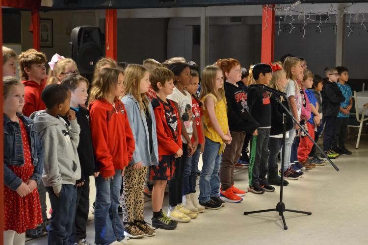 Second-graders line up next to their classmates to sing "God Bless the U.S.A.” at a concert at American Legion Post 123 on Tuesday morning. Some students watched their teacher for a cue to begin while others shared a smile for the veterans. (Grace Mains/The Oglethorpe Echo)