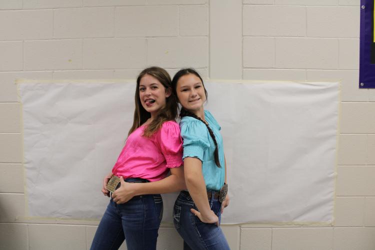 Naomi McPeake (left) and Mae Scoggins pose in their twin day theme. The two seventh graders matched in country outfits with big belt buckles. (Photo/Caleb Baldwin)