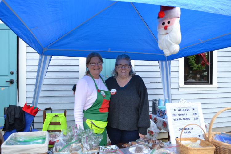 Debby Ferreiro and Sheryl Wall serve homemade cookies, cakes and more from the Community Club in Maxeys. Venders were set up along the side walk for parade watchers to enjoy some treats and warm drinks. (Grace Mains/the Oglethorpe Echo)
