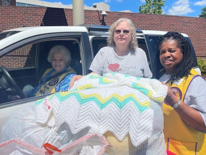 Corrine Thiel (from left), president of Oglethorpe County Lions Club, Virginia Sanders, founder of Covered with Love and Emma Walter, secretary of Oglethorpe County Lions Club display a blanket from Covered with Love to include in pajama packs. The club donates pajamas and other items to Piedmont Athens Regional for children with extended stays. (Submitted Photo).