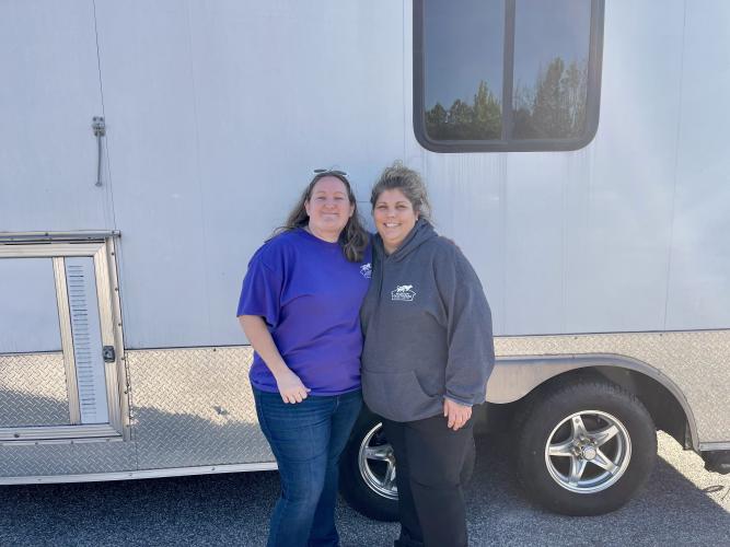 Madison Oglethorpe Animal Shelter Grants Coordinator Shaina Knight (left) and Shelter Director Erica Hendrix (right) standing in front of the trailer the shelter will operate the free vaccine clinic out of. The clinic is part of the MOAS Underserved Animal Project and is sponsored by the Banfield Foundation and MOAS Pets. (Lee Short/The Oglethorpe Echo)