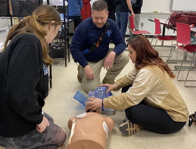 Oglethorpe County EMS Director Jason Lewis assists OCHS students Sarah Noltensmeier (left) and McKenna Wells (right) as they work through stations, each focusing on a different area. Other stations include bleeding control techniques, spinal immobilizations, airway management and patient assessment.