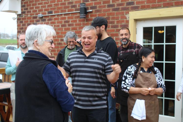 Linda Parish (from left), the Chamber of Commerce's tourism and hospitality director, hands ribbon-cutting scissors to Josh Robayo, the co-owner of Town and Country Kafe. The Chamber of Commerce hosted the ribbon-cutting ceremony to welcome the business into the county. (Sarah Myers/The Oglethorpe Echo)