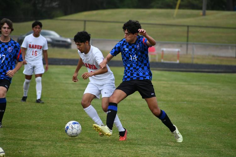 Sergio Alio (14) battles a Rabun County player for possession of  the ball during a Class A Division I soccer game on April 17. The  Wildcats scored two second-half goals to eliminate the Patriots  with a 3-1 victory. (Wade Cheek/For The Oglethorpe Echo)
