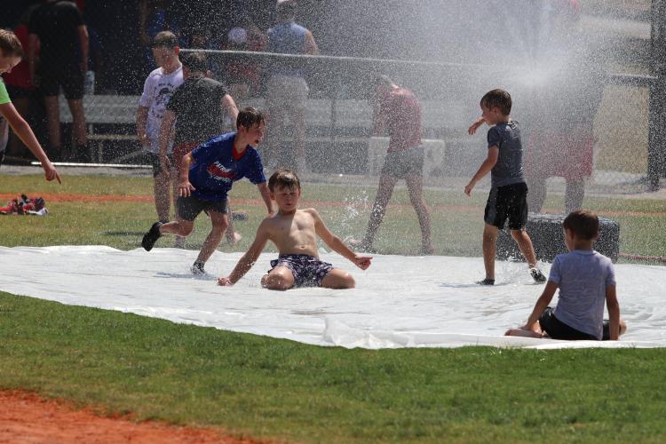 Lawson Smith (center) and other campers imitate a soccer “knee slide” goal celebration on the slip-n-slide after the baseball finished on June 26. OCHS baseball coach Mike Campbell focused on having fun at the camp. (Torin Smith/The Oglethorpe Echo)
