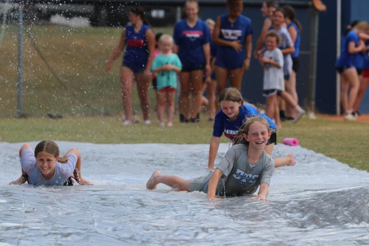 Lucie Sanders (left), Skyler Fleming (front) and Lilly Graham (back) go for a turn on the slip-n-slide at the end of the softball camp at OCHS last week. (Torin Smith/The Oglethorpe Echo)