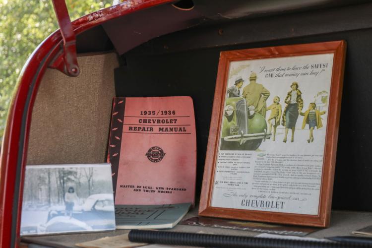 Archer’s collection of car manuals and vintage Chevrolet advertisements sit on display next to a picture of his mother in the back of his 1936 Chevrolet at the Firefly Cruise-In at the Oglethorpe County Courthouse, Sept. 22, 2024. He has 12 cars in his collection, keeping the original manuals from each model. “What really got me started with this particular model of car is that my mother had it,” Archer said.