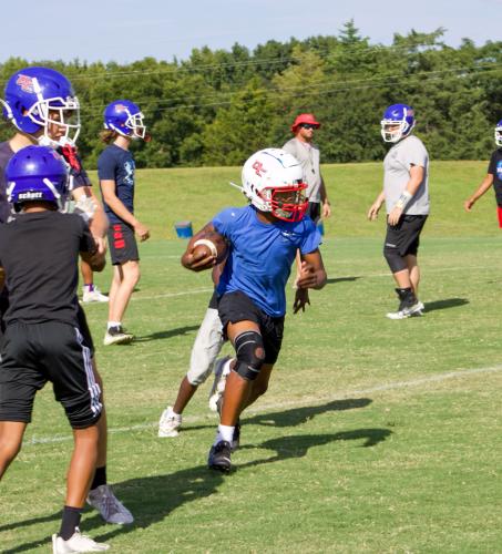 Brennan Brown weaves his way through defenders at a recent OCMS football practice. The Patriots are 5-0 this season.