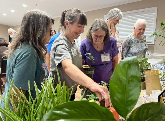 Vickie Coker (middle) and PlowShare members browse raffle items at PlowShare's 10 year anniversary meeting on Sept. 9, 2024. The raffle was free to enter, and everyone in attendance was able to choose an item to take home. (Ella Kroll/Oglethorpe Echo)