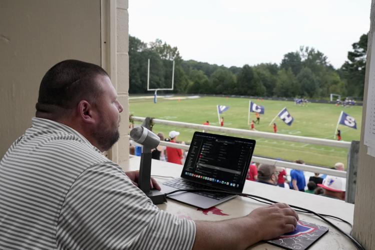 OCHS football announcer and Mt. Pleasant Community Church Pastor Levi Taylor looks on from the press box of Patriot Stadium as OCHS banners wave across the field to signal the start of the Patriots’ football game against Washington-Wilkes on Aug. 30. As the team storms the field, Taylor announces their arrival to signal the start of Friday night football in Oglethorpe County. (Saylor Williams/The Oglethorpe Echo)