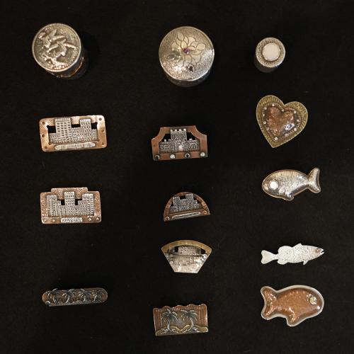 Bobby Teller showcases a selection of his handmade pins and containers on a black tablecloth at his house in Crawford. He also makes rings and other jewelry, silverware, hollowware and more. (TY JOHNSTON/THE OGLETHORPE ECHO)
