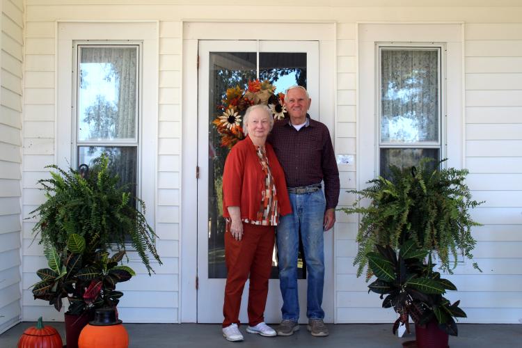 Rosa and Roger NeeSmith pose on the front porch of their home on Monday, Oct. 21 in Lexington, Georgia. The home originally had a wraparound porch that was altered to accommodate a dining nook in the kitchen, a laundry room and a carport. “The house originally had a wrap around this part where the carport is now, and the people that had it before we did, he was a meteorologist in Athens, he poured cement, and I guess the wood was rotten,” Roger NeeSmith said. (Emily Slepsky/The Oglethorpe Echo)