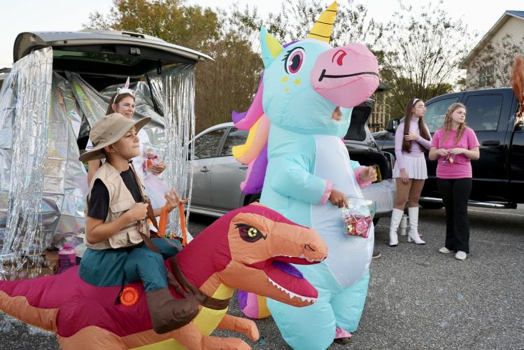 Sawyer Pittard, who is 11, stands ready to pass out candy from his unicorn themed trunk at this year's Trunk or Treat event. Inflatable costumes were a big hit this year with various animals making an appearance in extravagant blown-up versions throughout the night. (Saylor Williams/The Oglethorpe Echo)