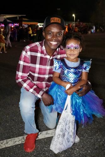 Williamson Sintyl, Chairman of the Chamber of Commerce, smiles with his daughter as they make the rounds, collecting candy and spending time with the community. Sintyl attended the annual Trunk or Treat event with his family for the fourth time on Thursday. “This community has a special place in my heart, because I never feel a stranger in this community,” Sintyl said. “This is where my family belongs. We've strived to serve, to give, to make an impact here, and we are so grateful to be in this community.”