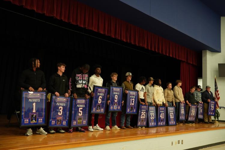 Senior football players line up across the stage after being presented with their framed jerseys at the OCHS awards ceremony in the cafeteria on Monday night.  (Saylor Williams/The Oglethorpe Echo)